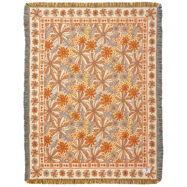 Image of flat woven throw with fringing on four sides, with a floral pattern in shades of light orange, light blue and beige.
