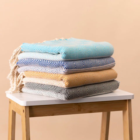 Bundle of four Capri hammam towels in different colours on a stool.