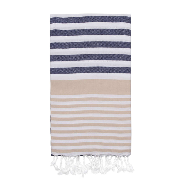 Image of a folded hammam towel with beige and navy blue stripes on a white background, with white knotted tassels.