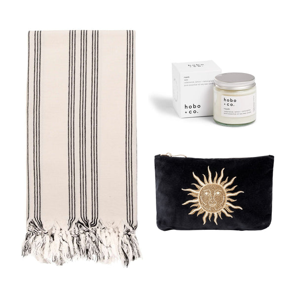 Black and white striped cotton hammam towel, black velvet embroidered pouch and a hobo & co jar candle on a white background