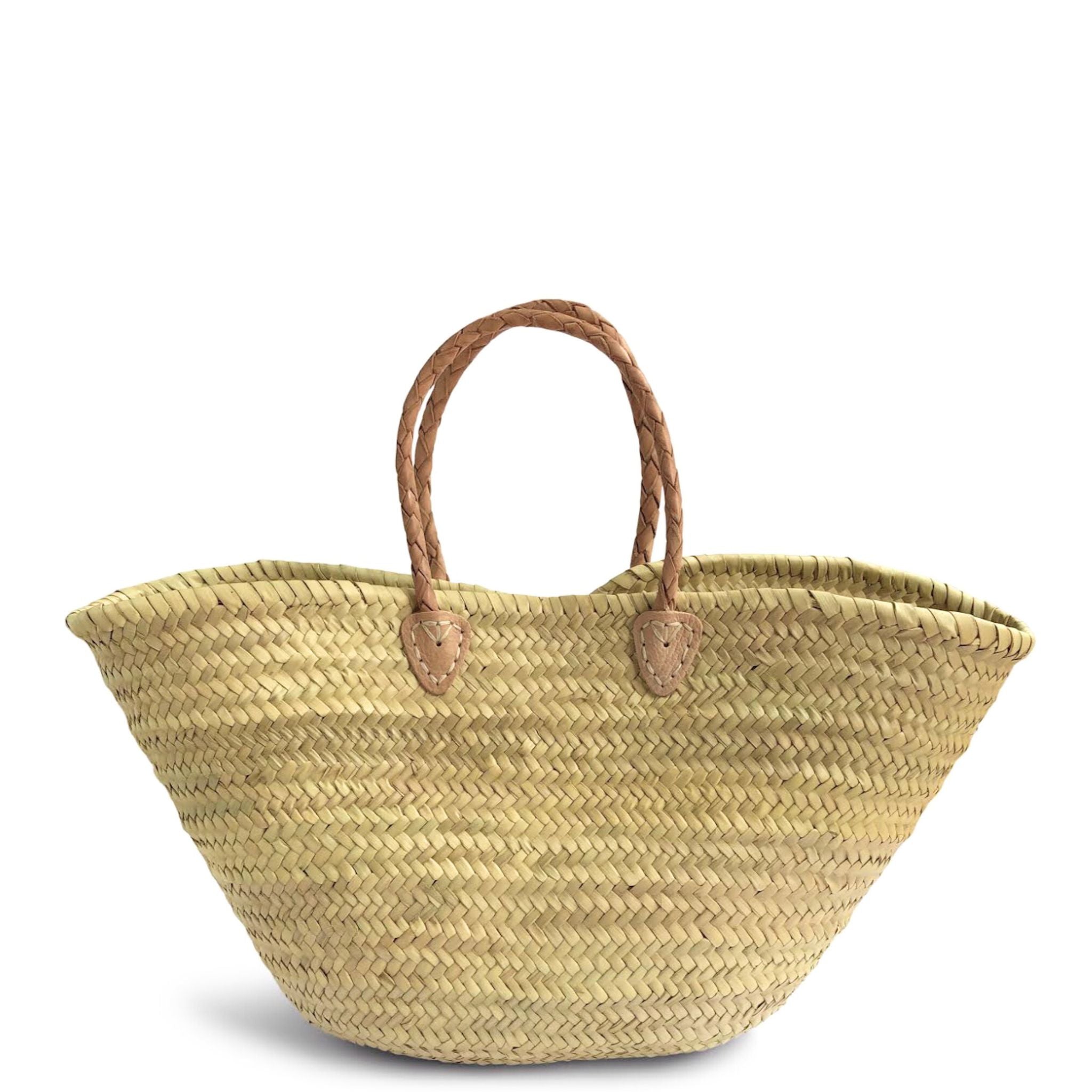 A French style straw basket with plaited natural leather handles on a white background.