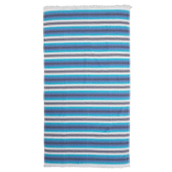 Image is of a flat hammam towel in varying shades of blue, turquoise and white, with white eyelash fringing at both ends. Sold by Sand and Salt.