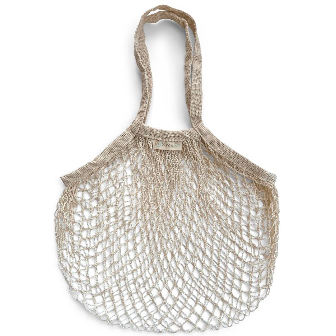 Image is of a natural cream coloured string shopping bag flat against a white background. Organic cotton string bag.